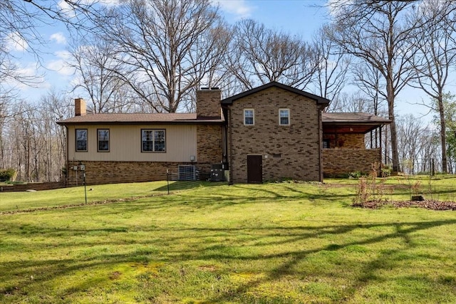 back of property with a chimney, brick siding, and a yard
