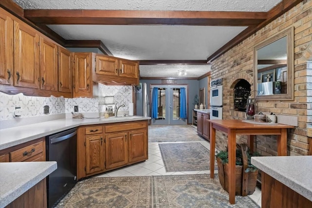 kitchen with beamed ceiling, light countertops, dishwashing machine, and a sink