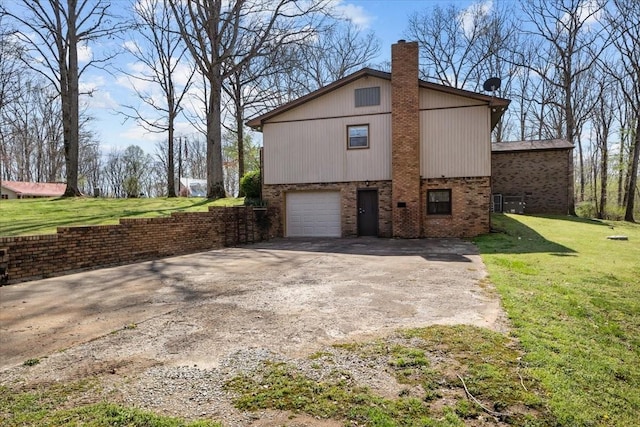 view of home's exterior featuring brick siding, driveway, a chimney, and a lawn
