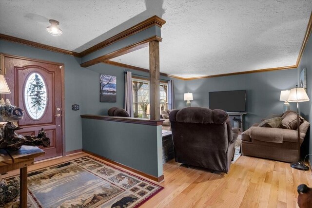 living room featuring light wood-style flooring, a textured ceiling, a wealth of natural light, and ornamental molding