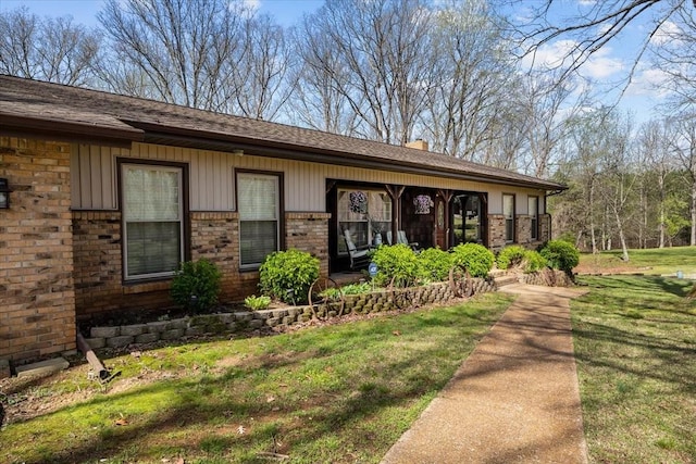 entrance to property featuring a chimney, brick siding, and a yard