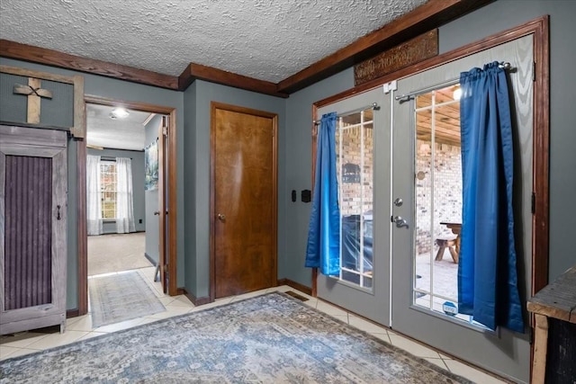 foyer entrance featuring french doors, tile patterned flooring, and a textured ceiling