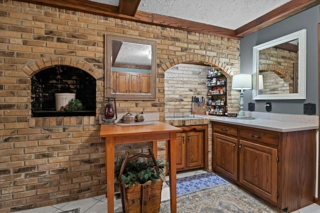 bar featuring brick wall, a textured ceiling, and light tile patterned floors