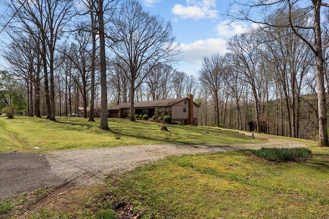 view of front of home with dirt driveway, a front lawn, and a chimney