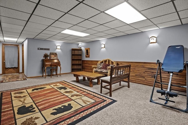 living area featuring wood walls, carpet flooring, and a drop ceiling