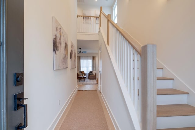 stairway with visible vents, baseboards, carpet, a ceiling fan, and a high ceiling