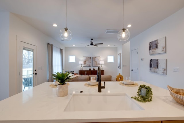 kitchen with open floor plan, a sink, a kitchen island with sink, and light countertops