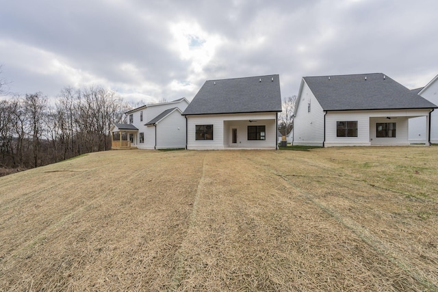 back of property with a gazebo, a yard, a shingled roof, and ceiling fan