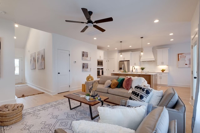 living room featuring ceiling fan, baseboards, light wood-style floors, and recessed lighting