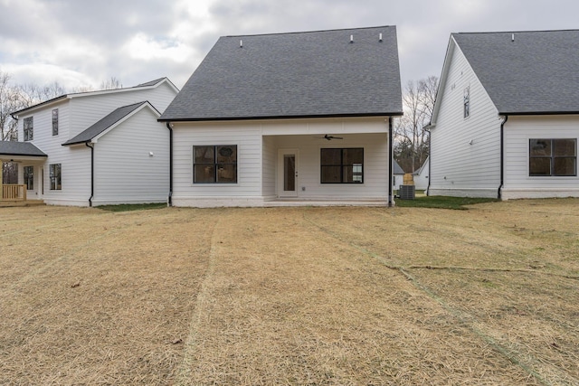 back of property with a yard, central AC unit, a shingled roof, and ceiling fan