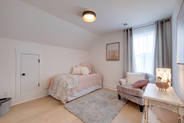bedroom with light wood-style floors, vaulted ceiling, visible vents, and baseboards