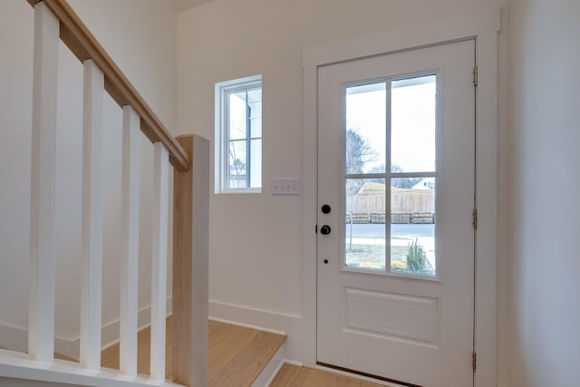 doorway to outside with light wood-style flooring, stairway, and a healthy amount of sunlight