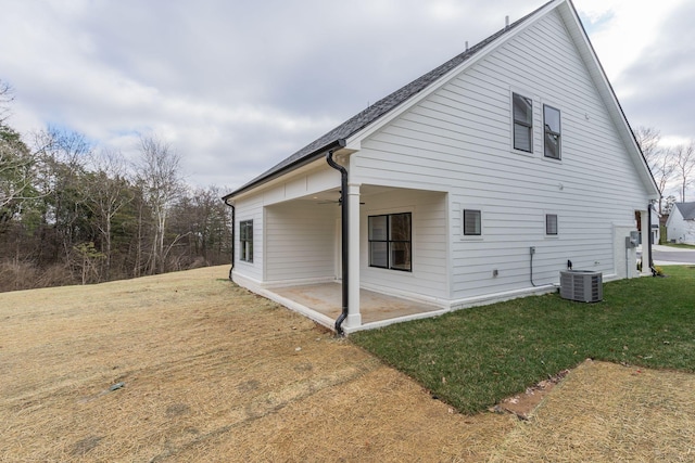 view of home's exterior with ceiling fan, central AC unit, a yard, and a patio