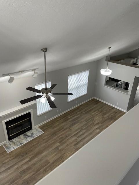 detailed view of a ceiling fan, a fireplace, and wood finished floors