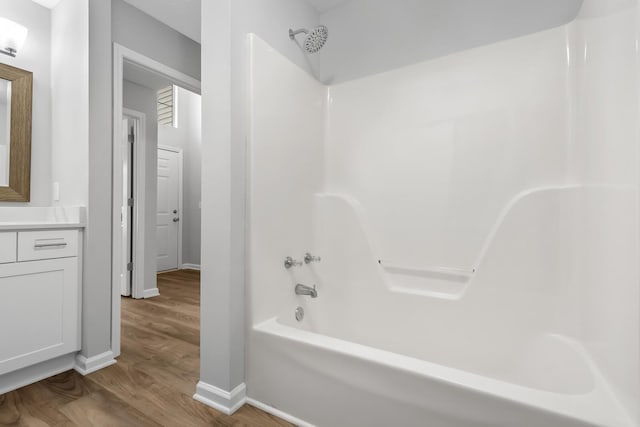 bathroom featuring  shower combination, wood finished floors, baseboards, and vanity