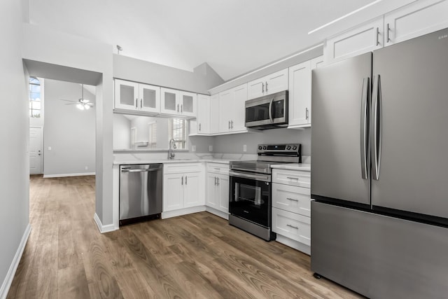kitchen with stainless steel appliances, a ceiling fan, light countertops, vaulted ceiling, and white cabinets