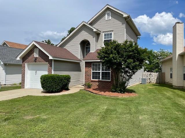 traditional-style home with brick siding, a garage, concrete driveway, and cooling unit