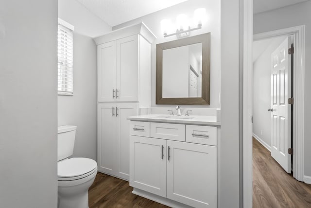 bathroom featuring wood finished floors, toilet, vanity, and baseboards