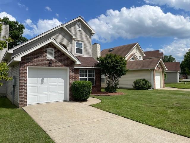 traditional home with brick siding, driveway, and a front lawn