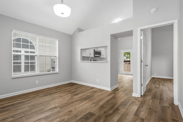 spare room with dark wood-style floors, lofted ceiling, and baseboards