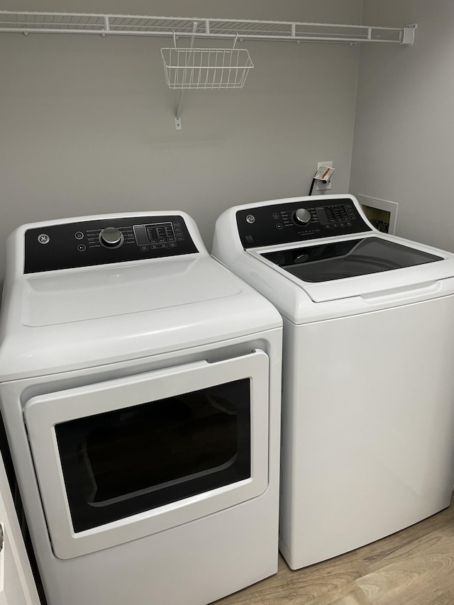 clothes washing area featuring washing machine and dryer and light wood-style flooring