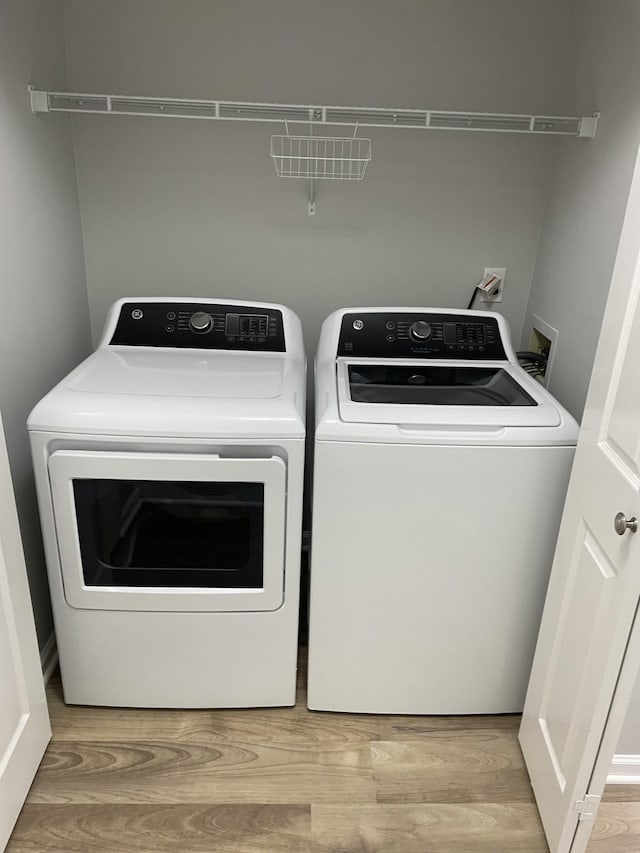 washroom with separate washer and dryer and light wood-style floors