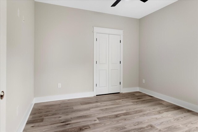 unfurnished room with baseboards, a ceiling fan, and light wood-type flooring