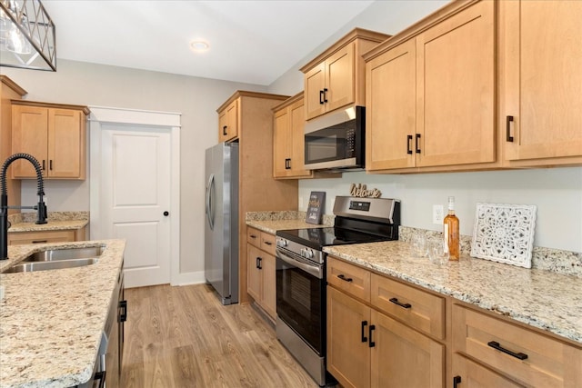 kitchen featuring light brown cabinets, appliances with stainless steel finishes, a sink, and light wood finished floors