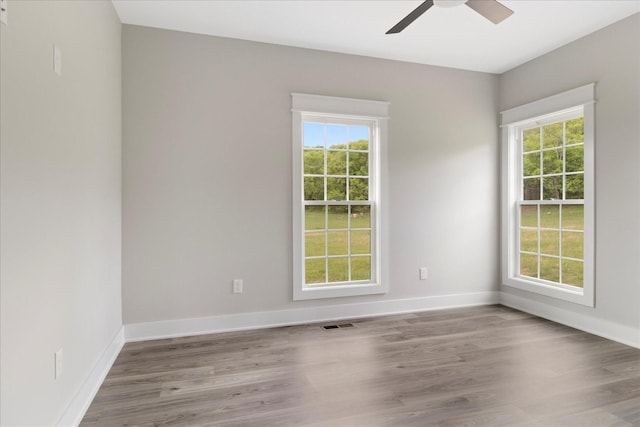 spare room featuring baseboards, wood finished floors, and plenty of natural light