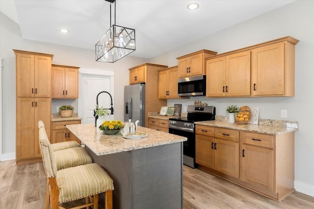 kitchen with an island with sink, a breakfast bar area, stainless steel appliances, a notable chandelier, and light stone countertops