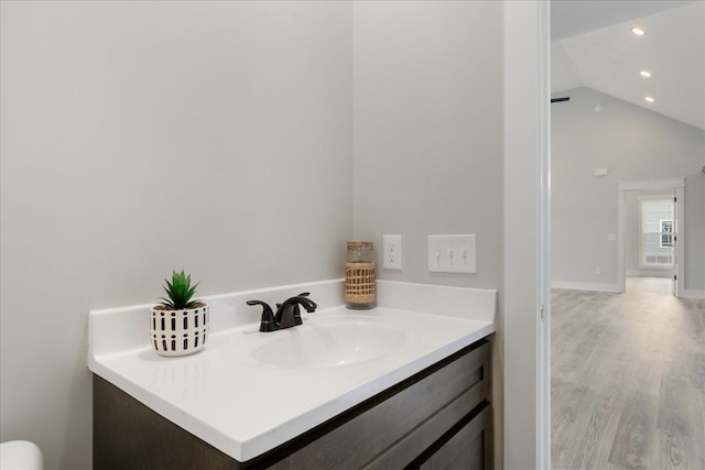 bathroom with lofted ceiling, vanity, wood finished floors, and recessed lighting