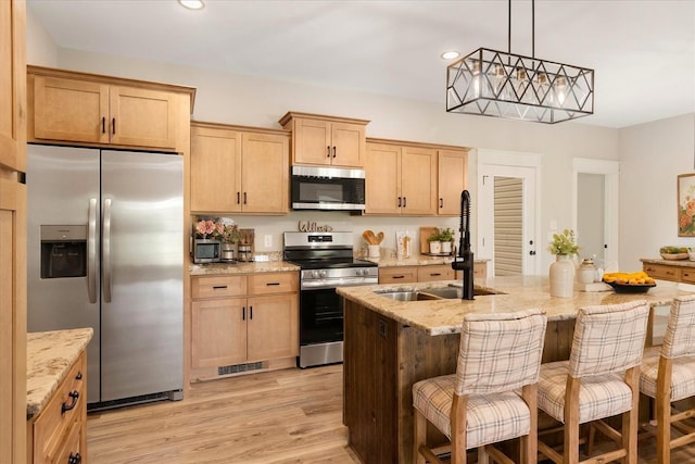 kitchen featuring appliances with stainless steel finishes, light stone counters, and a sink