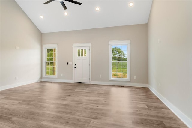 unfurnished living room with light wood-type flooring, a ceiling fan, baseboards, and vaulted ceiling