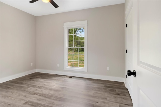 unfurnished room with baseboards, a ceiling fan, wood finished floors, and visible vents