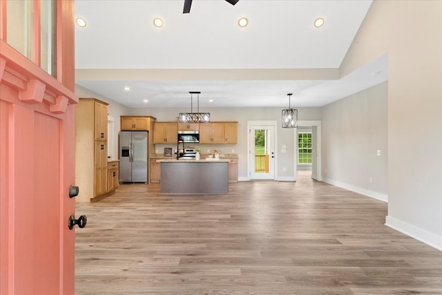 kitchen with open floor plan, light wood-type flooring, baseboards, and stainless steel appliances