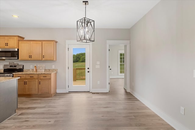 kitchen with light wood-style flooring, baseboards, pendant lighting, light stone counters, and appliances with stainless steel finishes