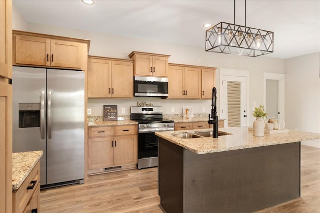 kitchen with light wood-style flooring, light stone countertops, appliances with stainless steel finishes, and a sink