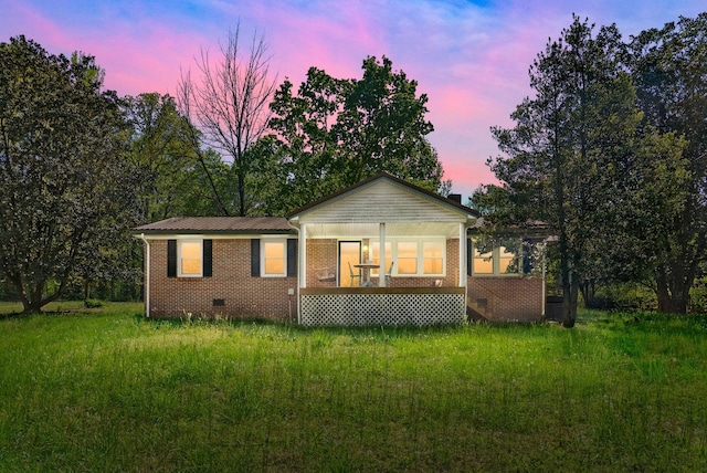back of house at dusk featuring brick siding, crawl space, and metal roof