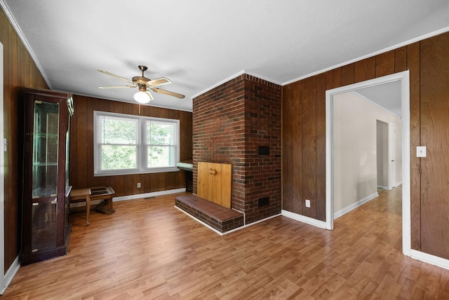 unfurnished living room featuring baseboards, a ceiling fan, wood walls, and light wood-style flooring