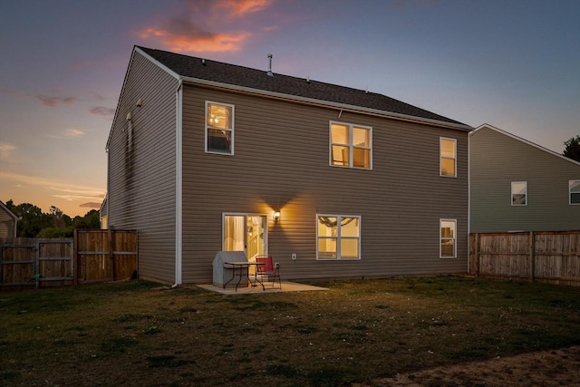 back of house featuring a fenced backyard, a gate, a patio, and a lawn