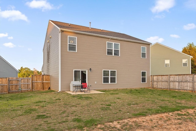 rear view of house with a fenced backyard, a yard, and a patio area