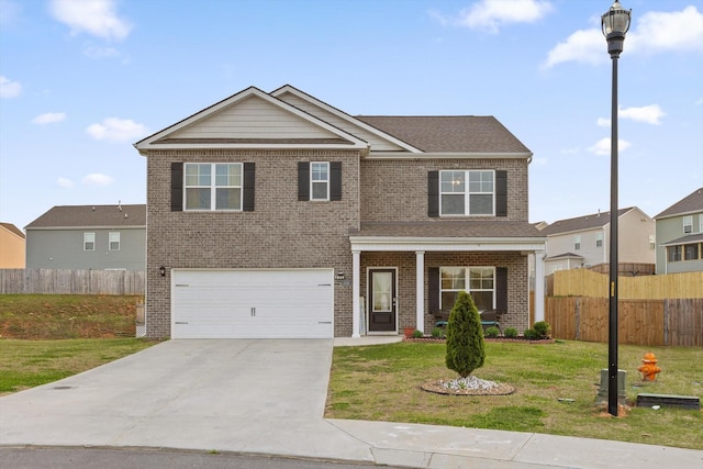 view of front of property with brick siding, concrete driveway, a front yard, and fence