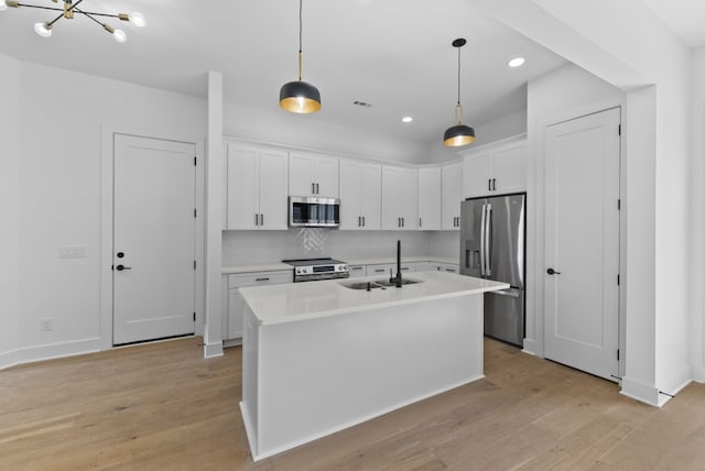 kitchen with white cabinets, stainless steel appliances, light countertops, and a sink