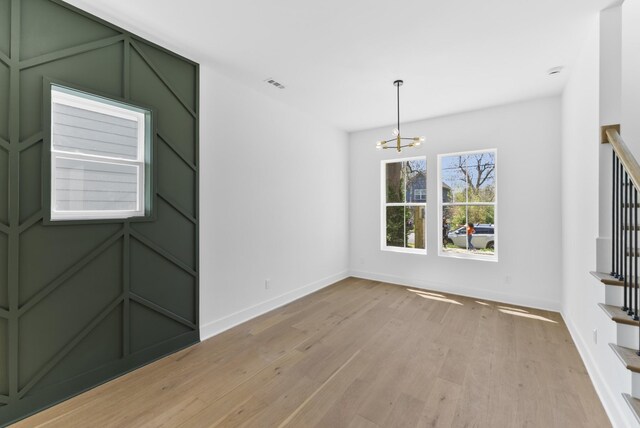 empty room with an inviting chandelier, stairs, visible vents, and baseboards