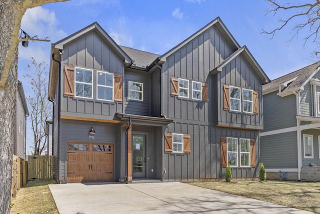 view of front of house featuring an attached garage, fence, board and batten siding, and driveway