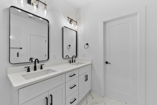 bathroom with marble finish floor, baseboards, a sink, and double vanity