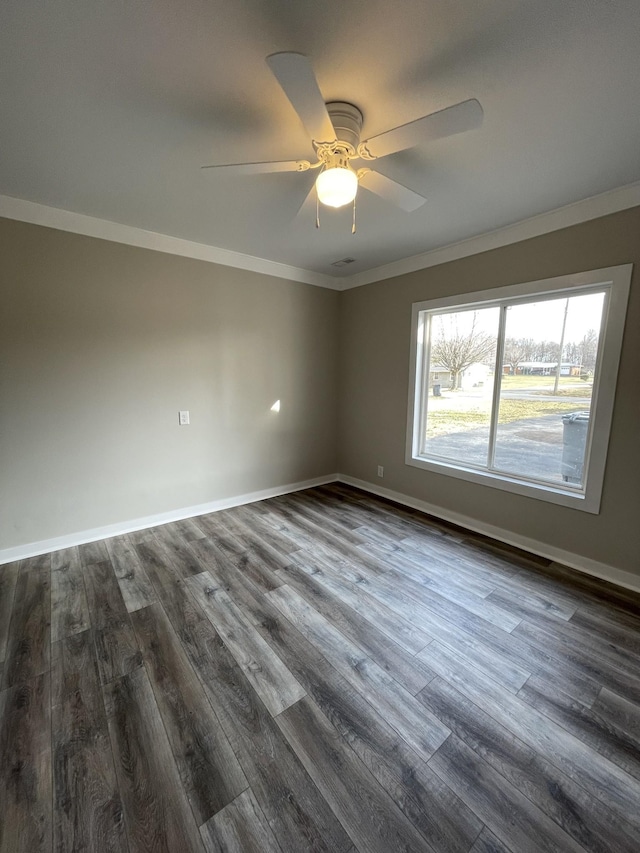 spare room featuring baseboards, dark wood finished floors, ceiling fan, and crown molding