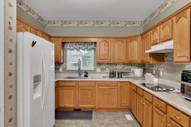 kitchen featuring white refrigerator with ice dispenser, under cabinet range hood, light countertops, black electric cooktop, and a sink