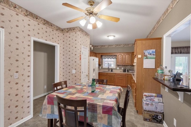 dining area featuring baseboards, ceiling fan, and light tile patterned flooring