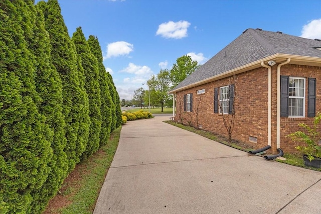 view of home's exterior featuring brick siding and roof with shingles
